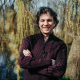 Foto van een man die met gekruisde armen staat, achter hem zijn bomen